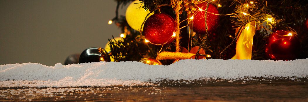 Wooden table with snow against christmas garlands on a pine