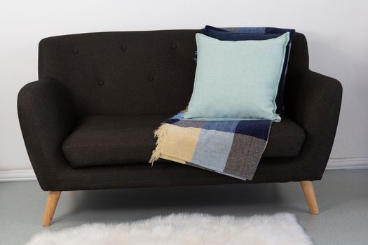 Close-up of cushions and blanket arranged on sofa