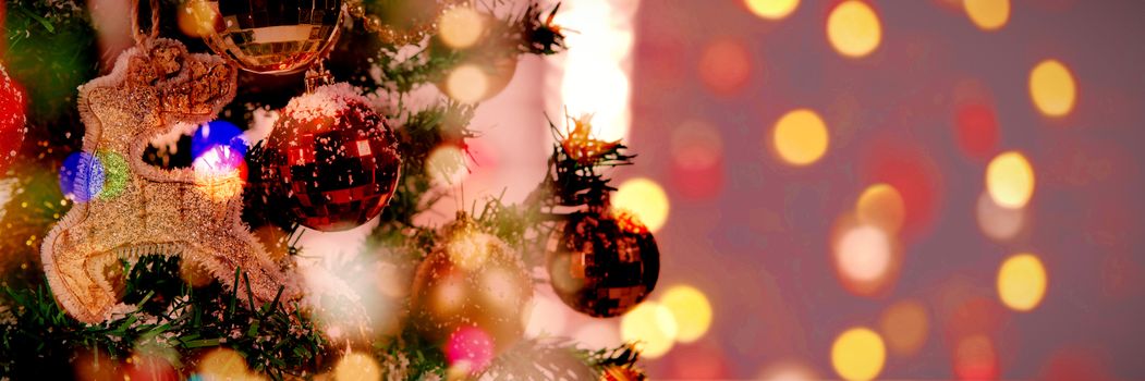 Defocused of christmas tree lights and fireplace against christmas ornaments hanging in tree