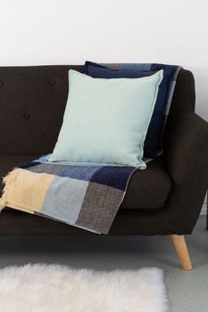 Close-up of cushions and blanket arranged on sofa