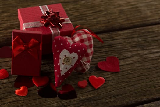 Heart shape decorations and gifts arranged on wooden plank