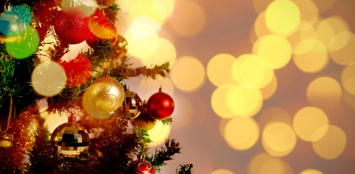 Defocused of Christmas tree lights and fireplace against red and gold christmas balls hanging in tree