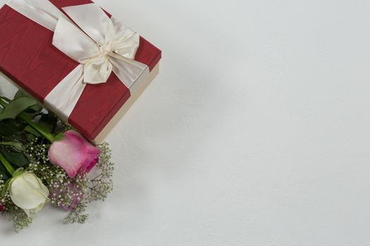 Close-up of flower bouquet and gift on white background