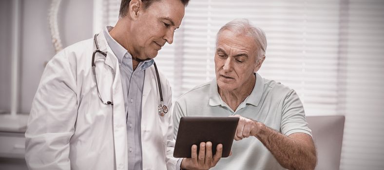 Doctor and senior patient using digital tablet in clinic