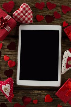 Heart shape decorations, gifts and digital tablet on wooden plank