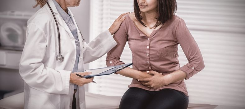 Patient suffering from stomach ache while consulting doctor in clinic