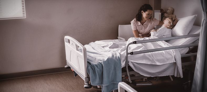 Female doctor consoling patient during visit in ward at hospital