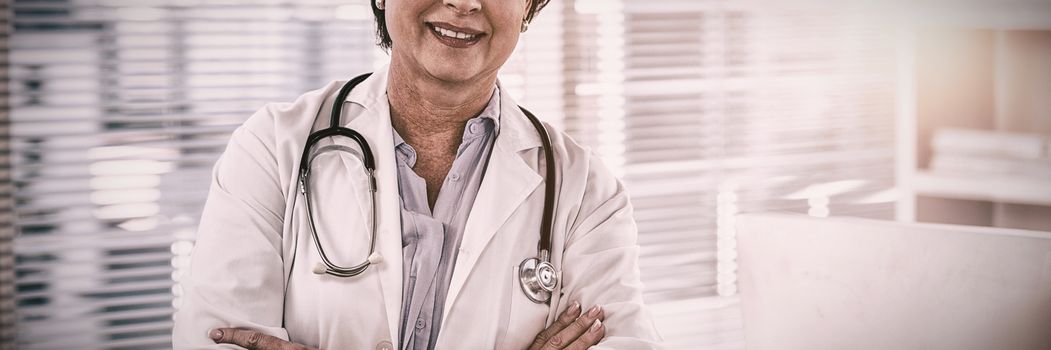 Portrait of a smiling female doctor standing with arms crossed at medical office