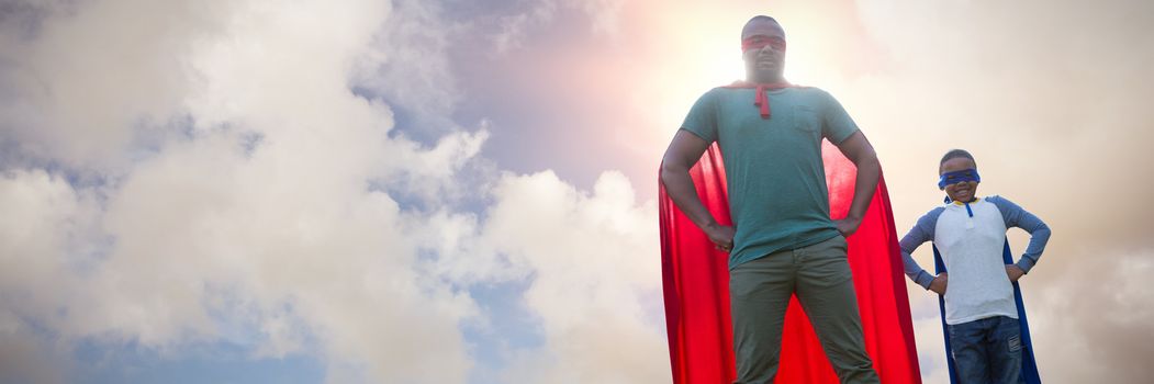 Father and son pretending to be superhero against blue sky with white clouds