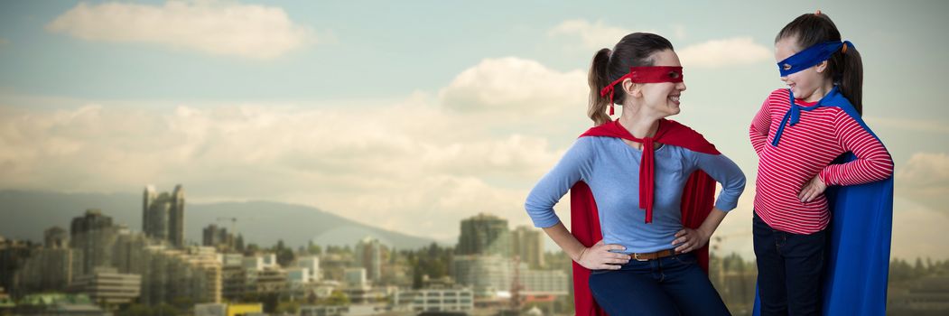 Mother and daughter pretending to be superhero against city