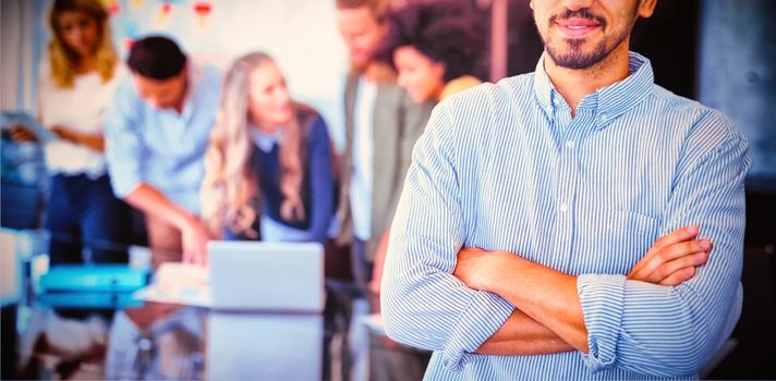 Portrait of young businessman standing with arms crossed at creative office