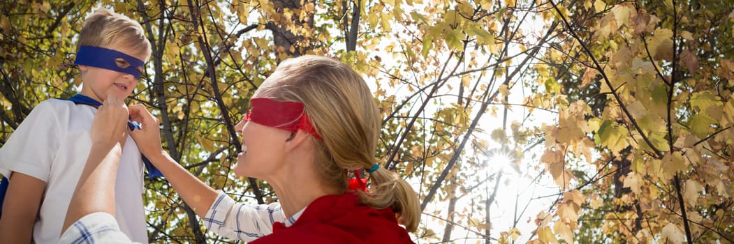 Mother and son pretending to be superhero against branch of maple leaves in autumn