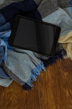 Close-up of digital tablet with blanket on wooden background