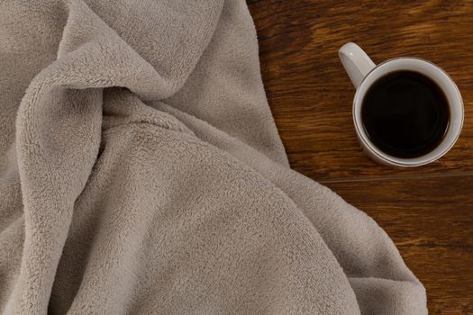 Close-up of blanket and black coffee on wooden background