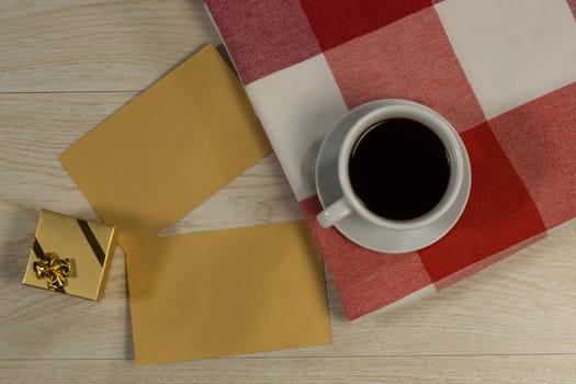 Close-up of gift box, card, textile and black coffee on wooden table