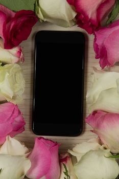 Close-up of mobile phone surrounded with rose flower