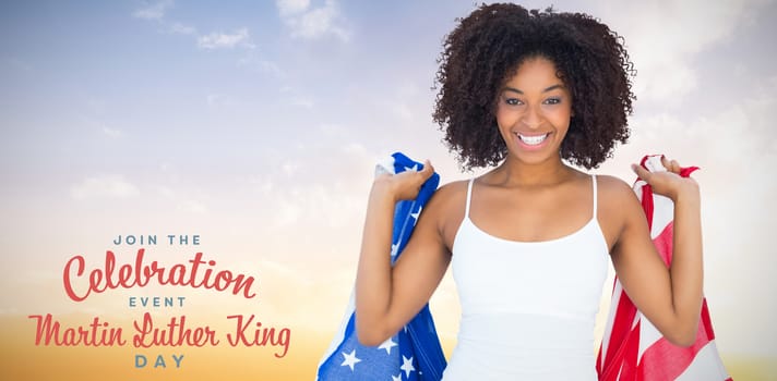 Pretty girl in white top holding american flag against sunset with clouds