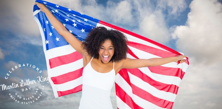 Pretty cheering girl in white top holding american flag against blue sky with white clouds