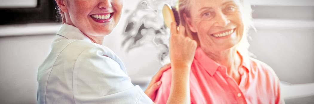 Female nurse combing hair of senior woman at home