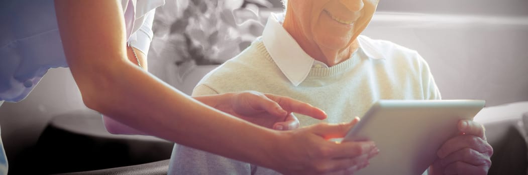 Female nurse showing medical report to senior man on digital tablet  at home