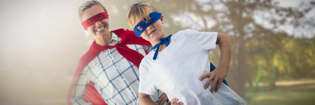 Mother and son pretending to be superhero against park on sunny day