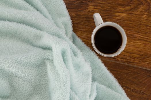 Close-up of blanket and black coffee on wooden background