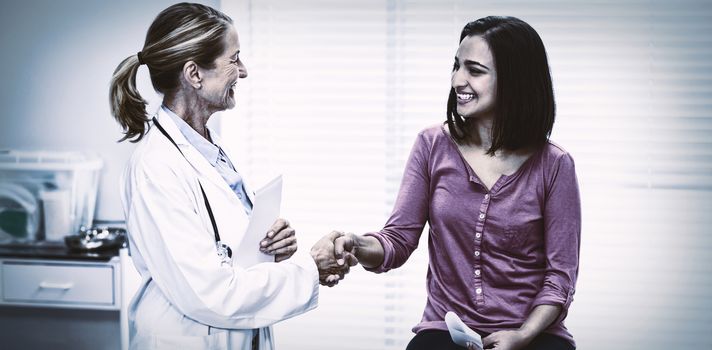 Female doctor shaking hands with patient in clinic