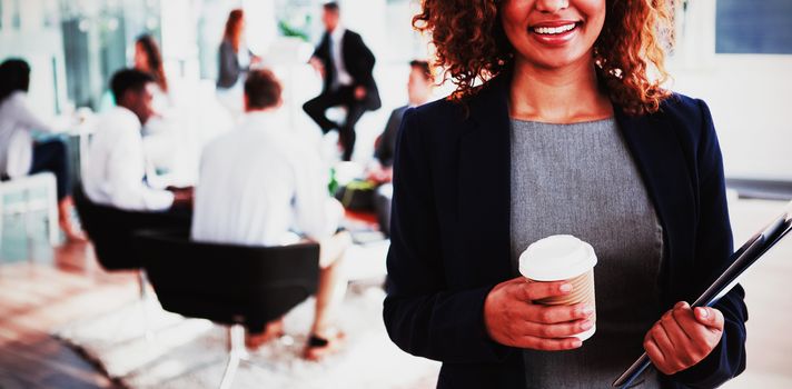 Portrait of smiling businesswoman holding disposable coffee cup in office