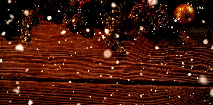 Snow falling against copy space with christmas ornament on a wooden background