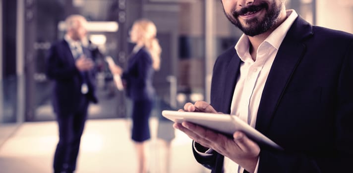 Portrait of businessman using digital tablet in office corridor