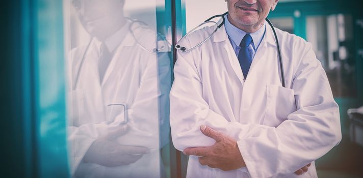 Portrait of male doctor standing with arms crossed in hospital