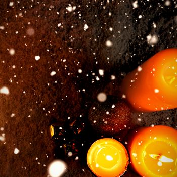 Snow falling against yellow christmas candles