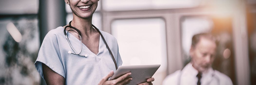 Portrait of smiling nurse with doctor using digital tablet in hospital