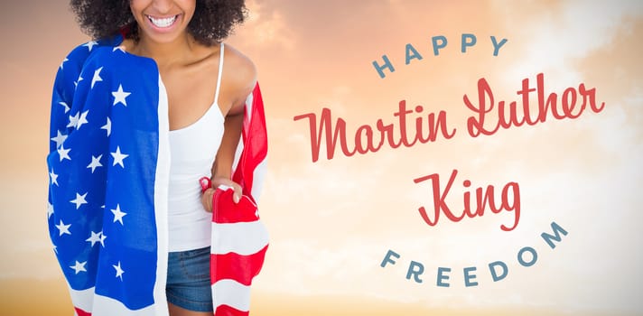 Pretty girl wrapped in american flag smiling at camera against sunset with clouds