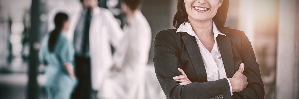 Portrait of businesswoman standing with hands folded at hospital