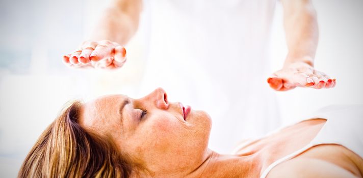 Midsection of therapist performing reiki treatment on woman at spa