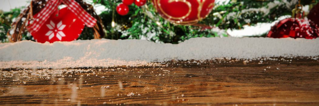 Wooden table with snow against close-up of christmas balls