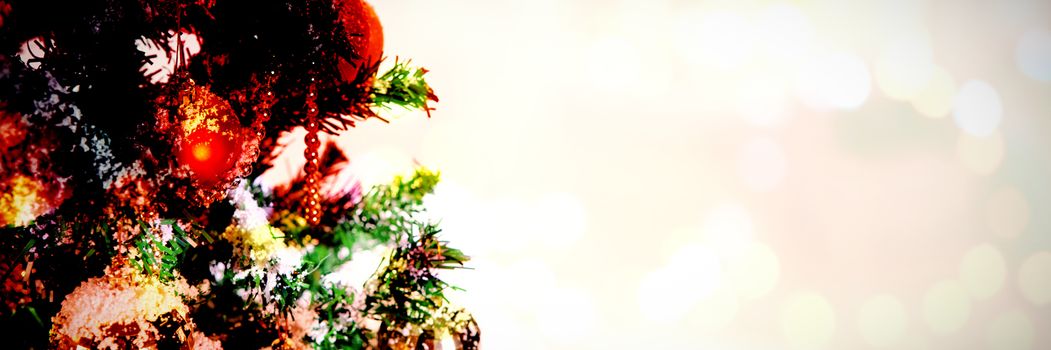 Composite image of table against christmas ornaments hanging in tree