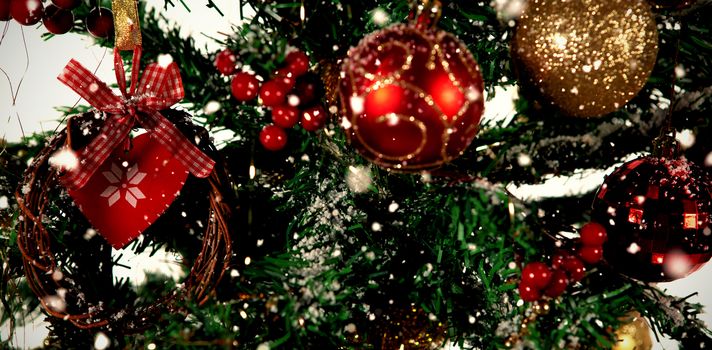 Snow falling against close-up of christmas balls