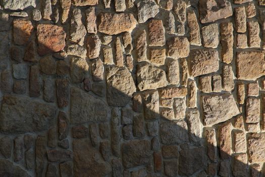 Dry stone wall texture background, in searing light and diagonal shadow.