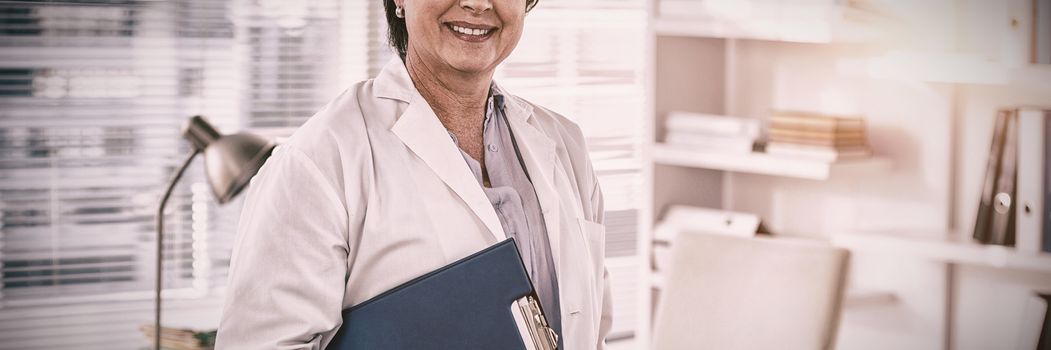Portrait of a smiling female doctor holding clipboard in medical office