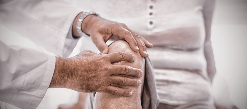 Physiotherapist giving knee therapy to senior woman in clinic