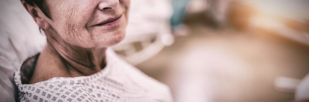 Portrait of smiling patient sitting on bed in hospital