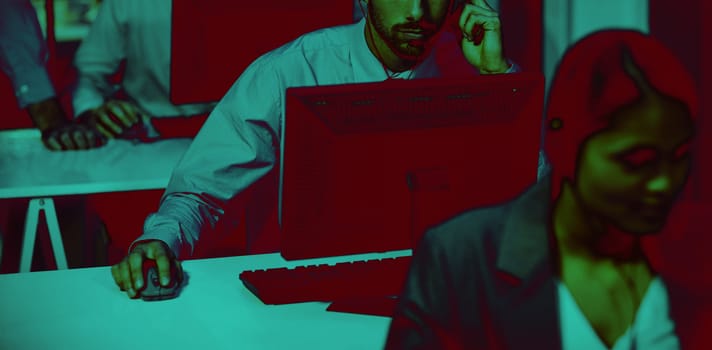 Businessman with headsets using computer in office at night