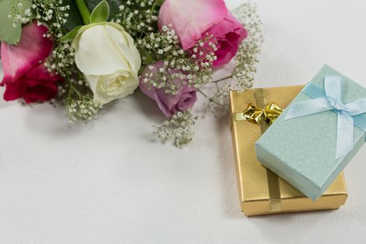 Close-up of flower bouquet and gift on white background