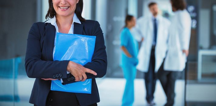 Portrait of confident businesswoman holding file in hospital