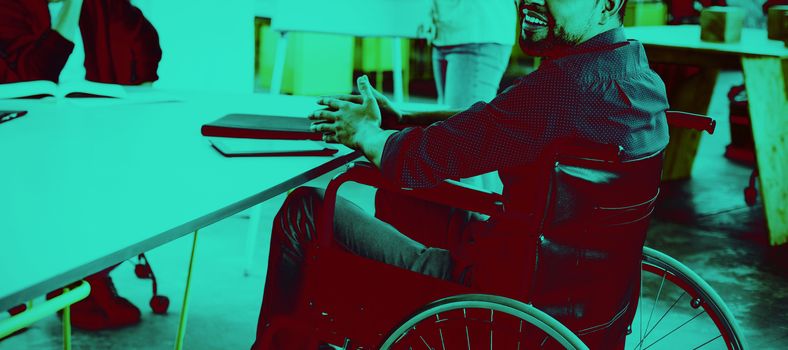 Portrait of smiling disabled business executive in wheelchair at meeting in office