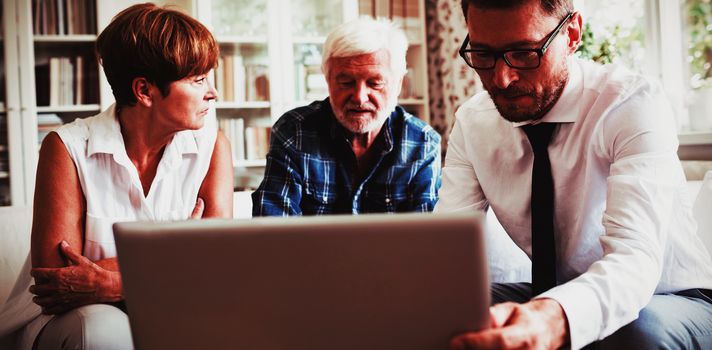 Senior couple planning their investments with financial advisor in living room