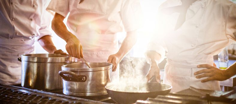 Chefs preparing food at stove in commercial kitchen