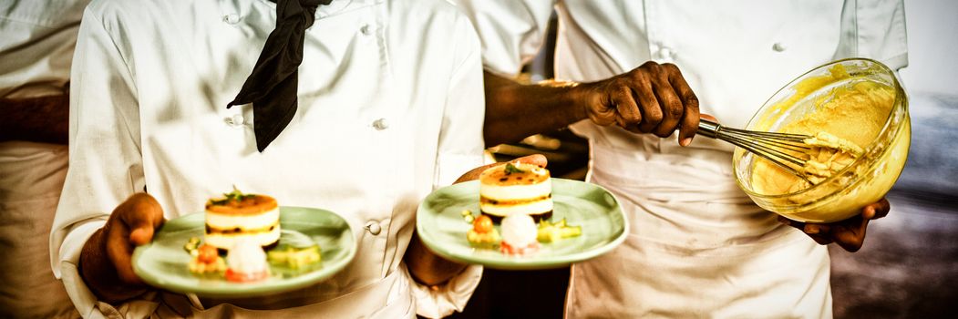 Female chef presenting dessert plates in commercial kitchen